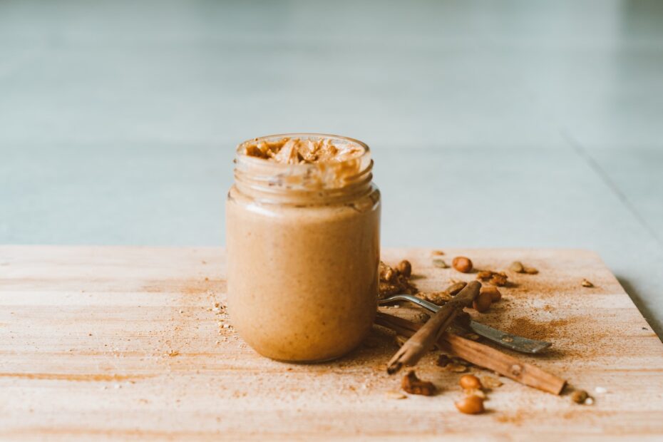 An image depicting a jar of creamy peanut butter surrounded by peanuts. {finish}